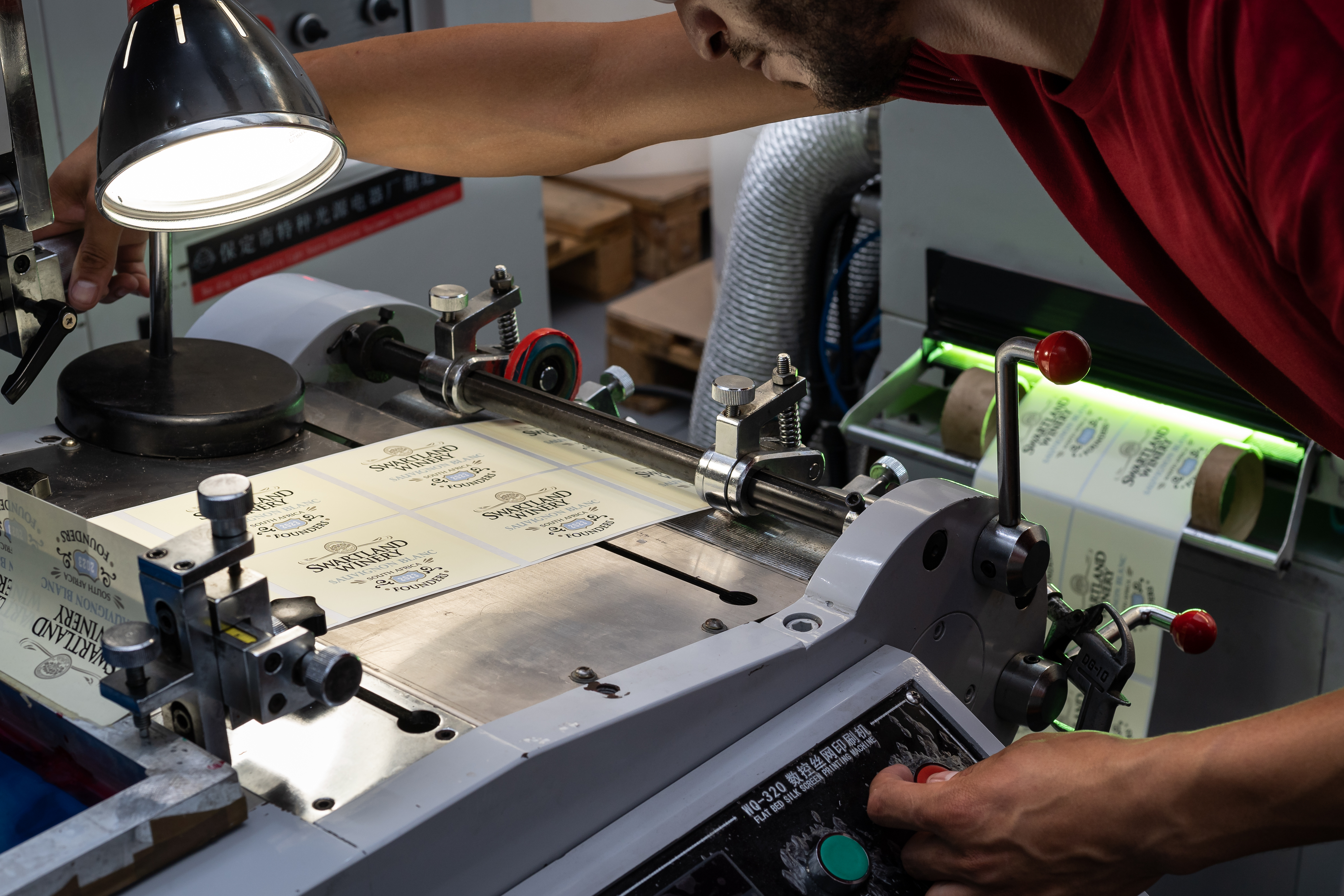 Technician working at silkscreen printing press with Swartland Winery labels